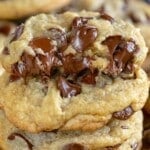 stack of chocolate chip cookies with a half cookie on top showing gooey chocolate chips