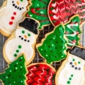 stacked christmas cookies in shapes like trees and snowmen with correlating frosting.