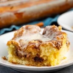 one square slice of cinnamon roll on a white plate.