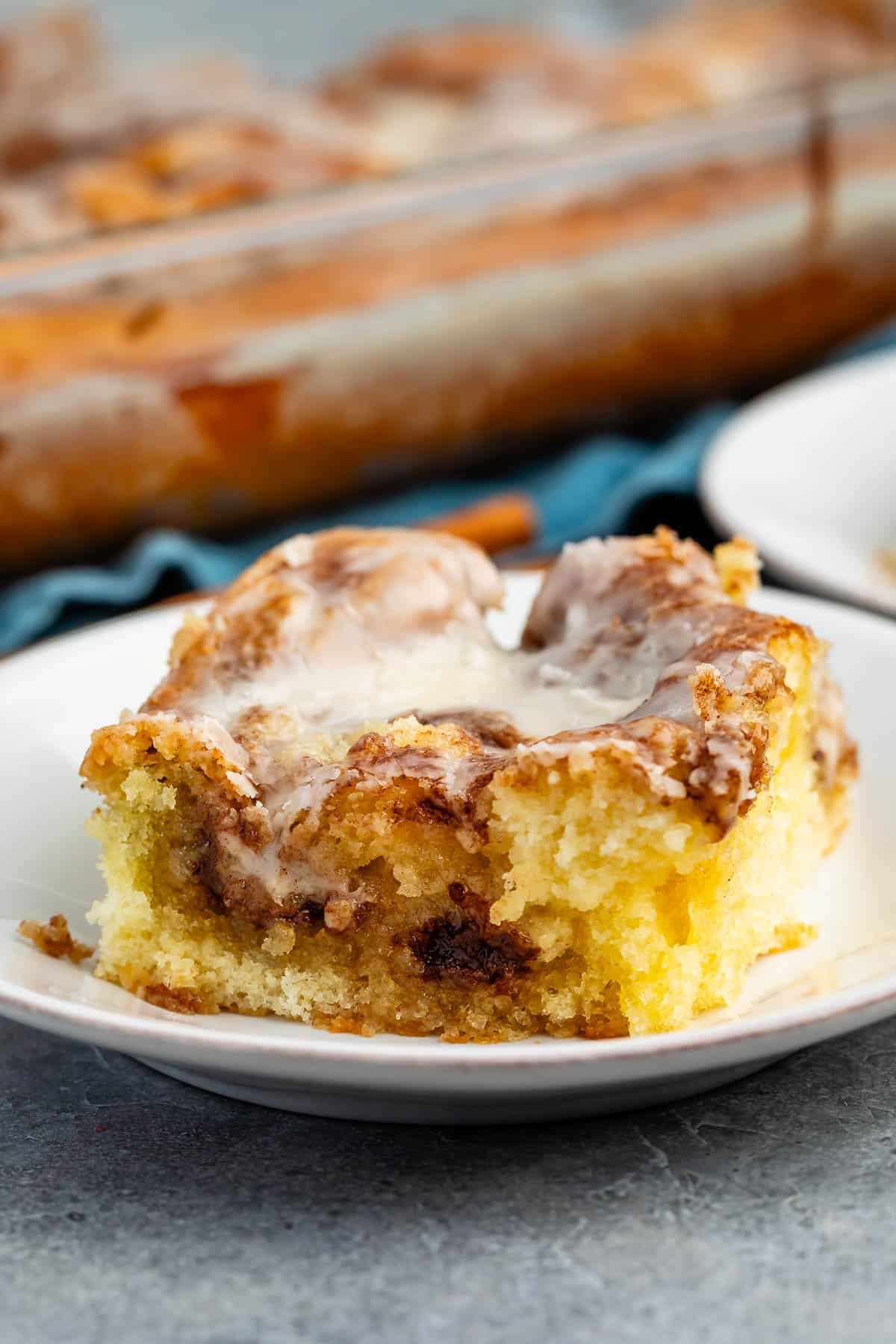 one square slice of cinnamon roll on a white plate.