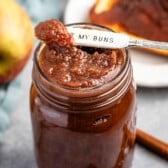apple butter in a mason jar with a spoon scooping it.
