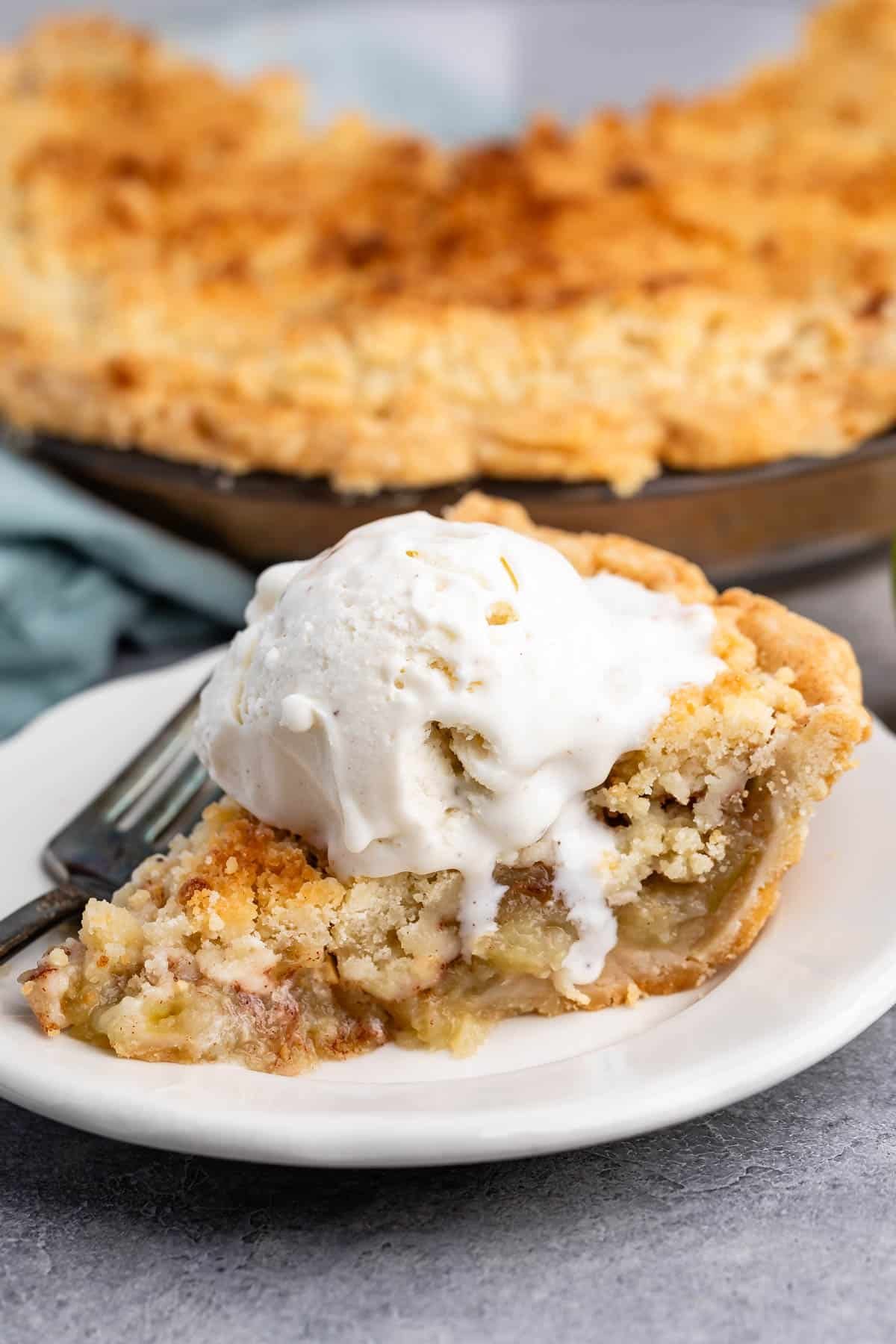 one slice of pie with crumble topping and vanilla ice cream on top.