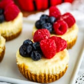 mini circular cheesecake with raspberries and blueberries on top.