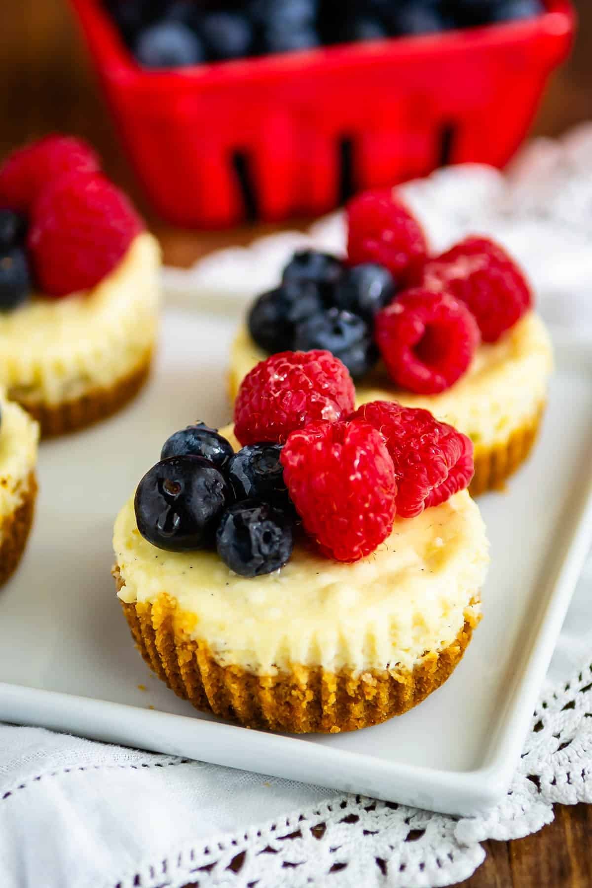 mini circular cheesecake with raspberries and blueberries on top.