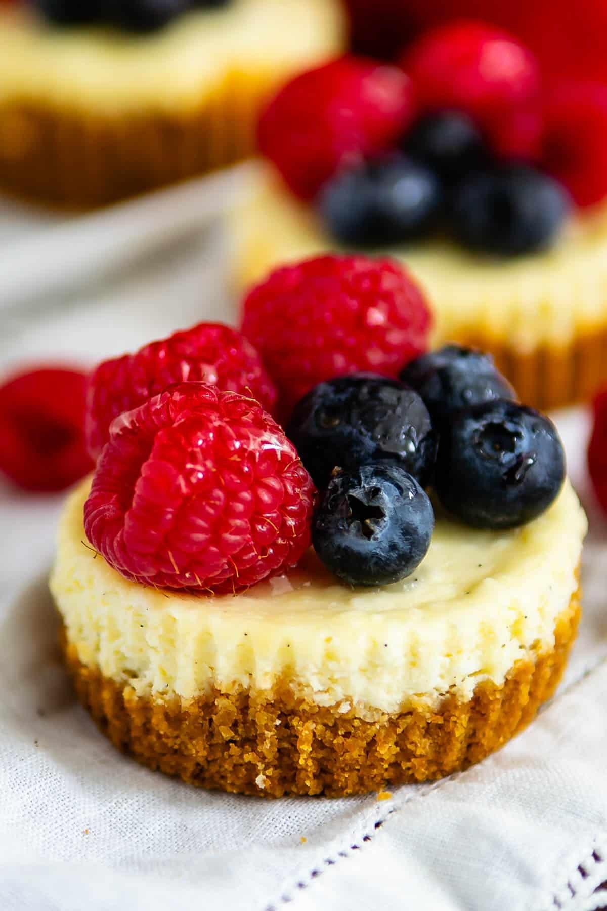 mini circular cheesecake with raspberries and blueberries on top.