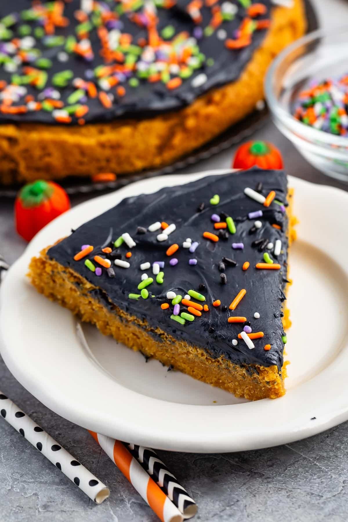 halloween pumpkin cookie cake with black frosting and sprinkles on top.