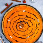 a circle cookie pizza with black frosting forming a spiderweb.