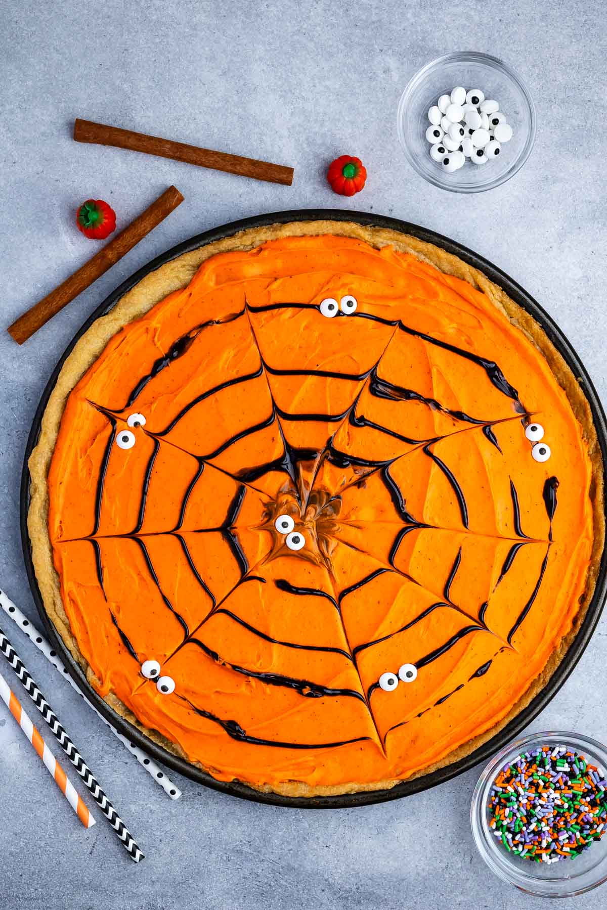 a circle cookie pizza with black frosting forming a spiderweb.