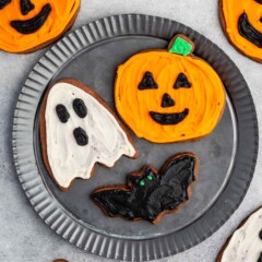 sugar cookies shaped like halloween characters and frosted with orange, white and black.