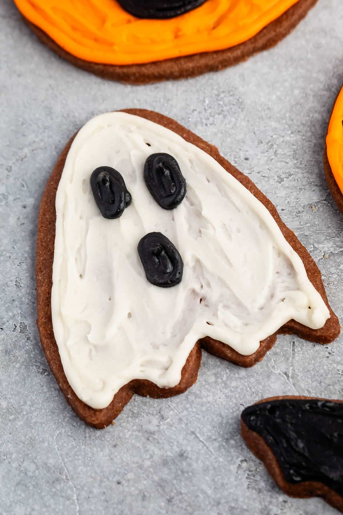 ghost shaped cookie with white and black frosting on top.