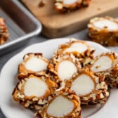 sliced pecan logs covered in caramel and pecans on a white plate.