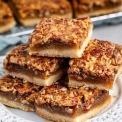 stacked pecan bars on a white plate.