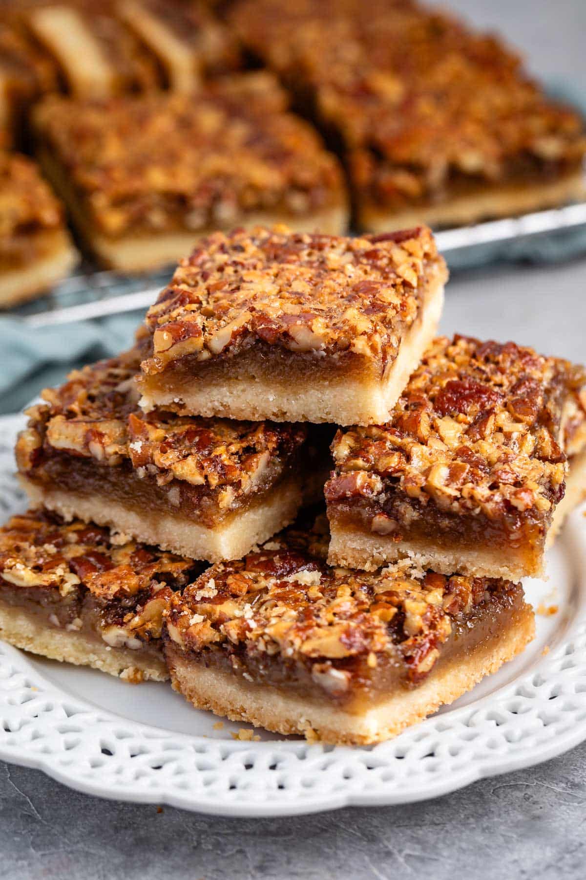 stacked pecan bars on a white plate.