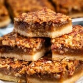 stacked pecan bars on a white plate.