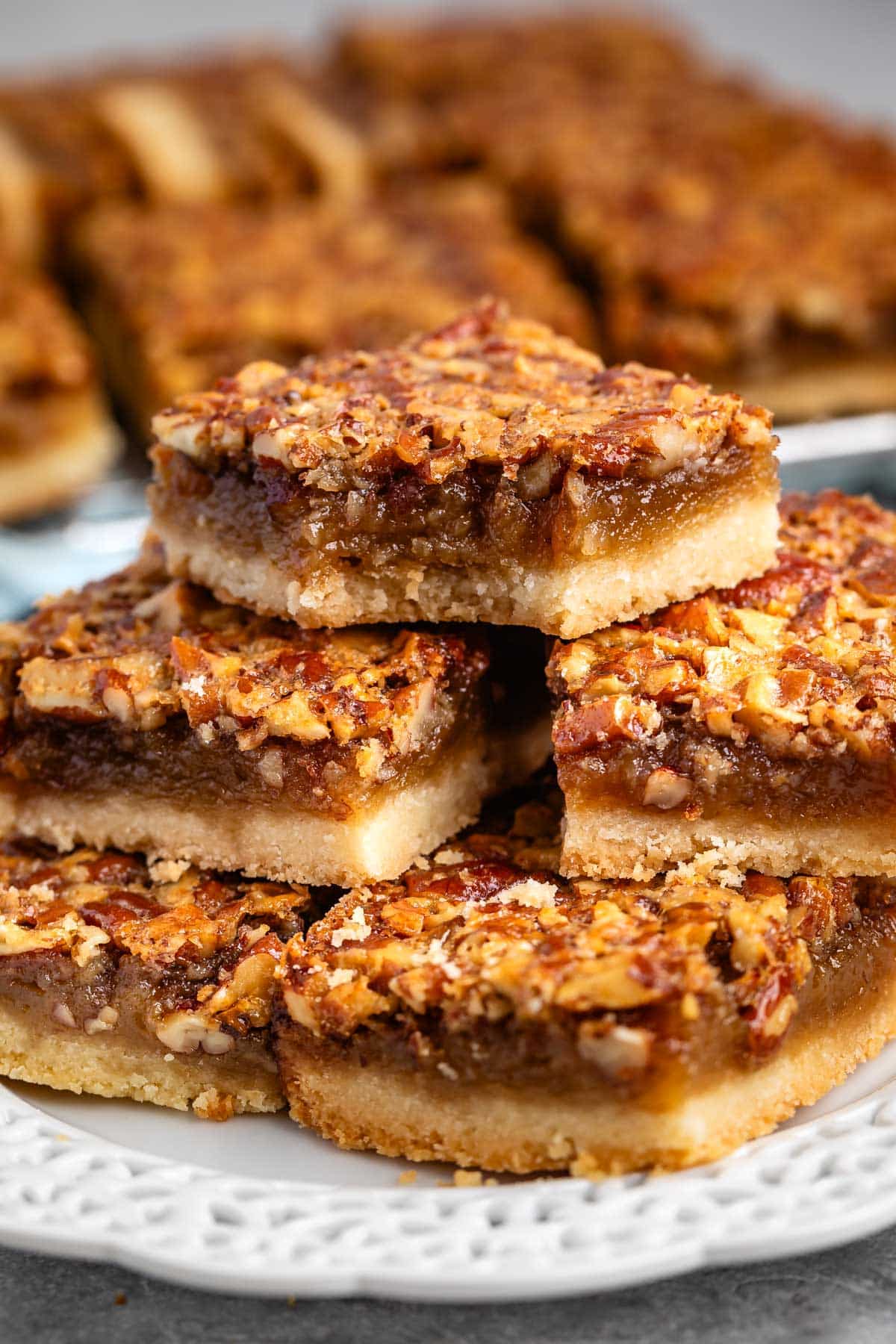 stacked pecan bars on a white plate.
