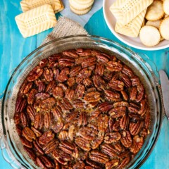 pecan dip in a clear bowl with a bunch of pecans on top.