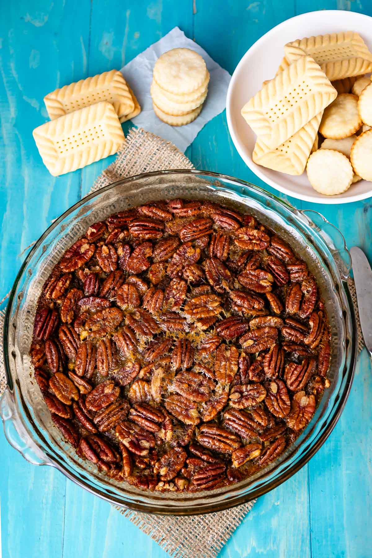 pecan dip in a clear bowl with a bunch of pecans on top.