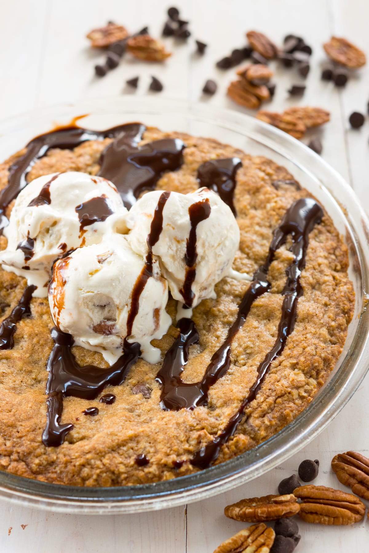 oatmeal cookie in pie plate with ice cream and chocolate sauce.