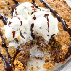 oatmeal cookie in pie plate with ice cream and chocolate sauce an slice missing.