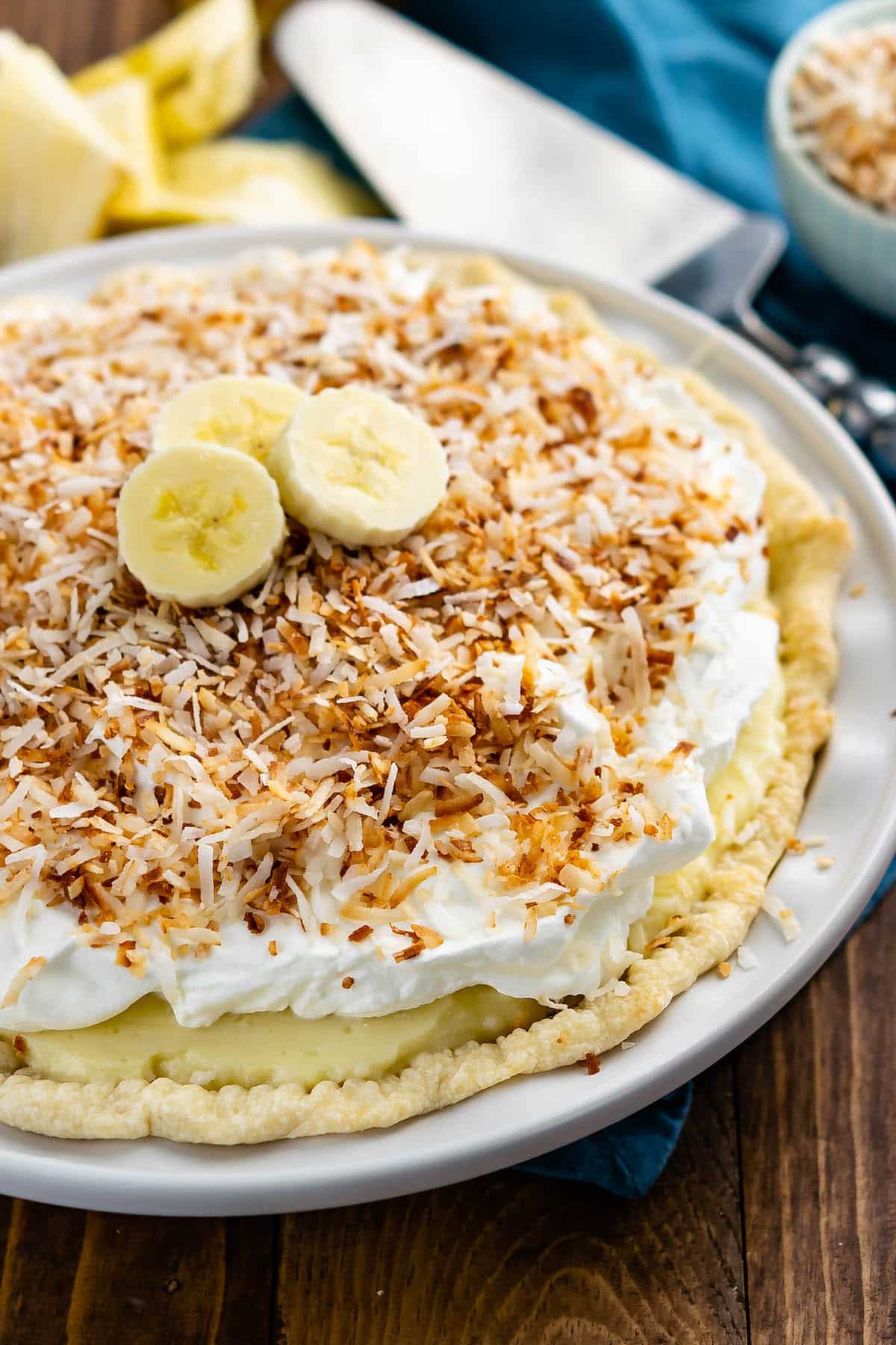 full banana cream pie topped with shredded coconut and sliced bananas.