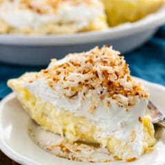 one triangle slice of banana cream pie topped with shredded coconut on a white plate.