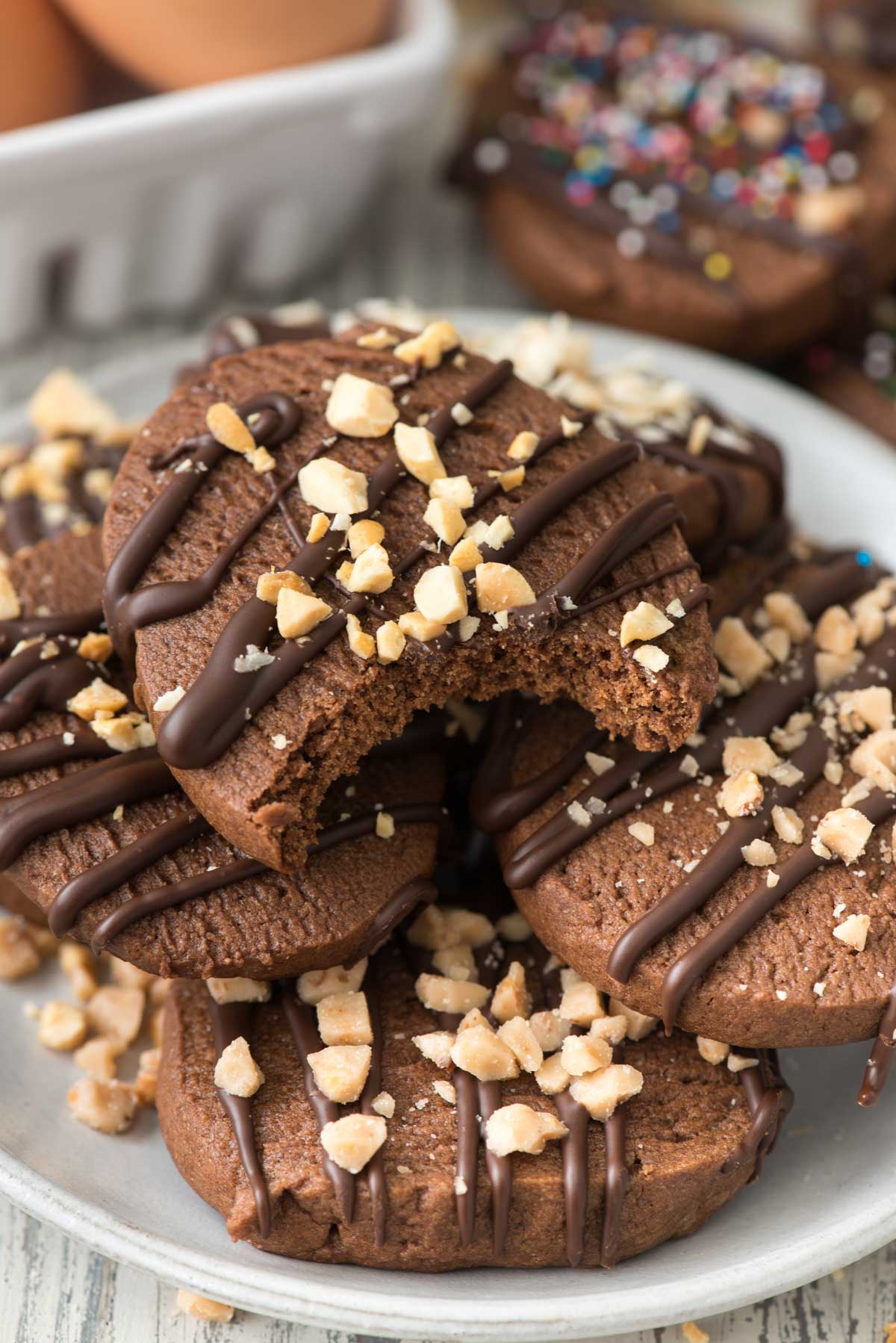 stacked chocolate cookies on a white plate with chocolate drizzled over top.