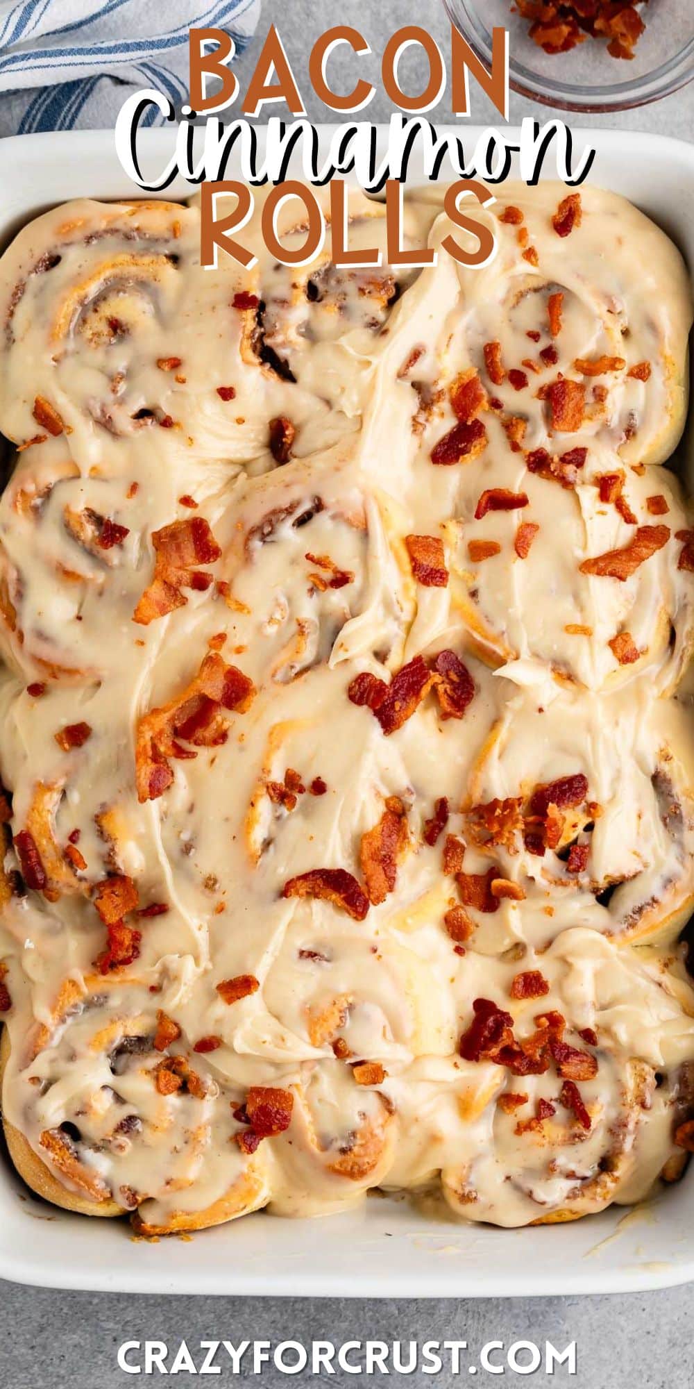 maple bacon cinnamon roll iced with white icing and sprinkled with bacon in a white dish with words on the image.