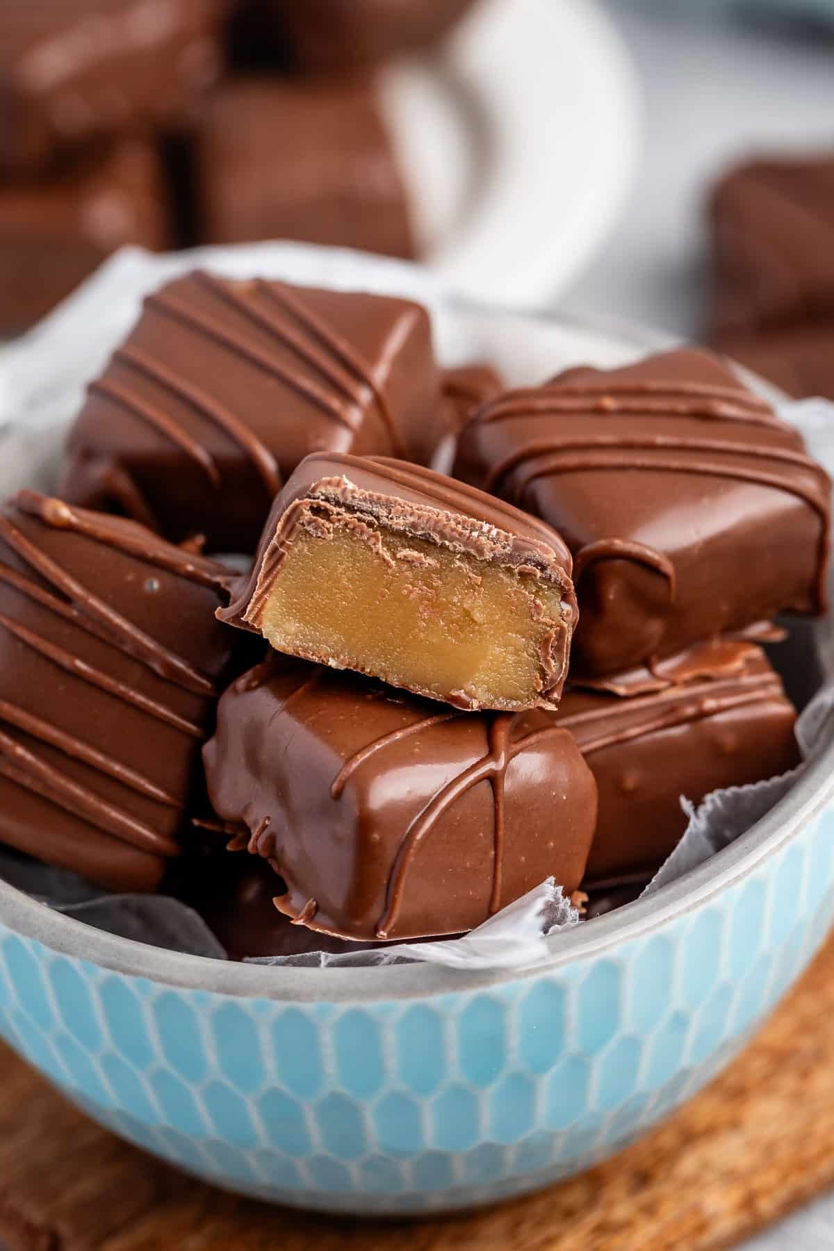 stacked butterscotch squares covered in chocolate in a light blue bowl.