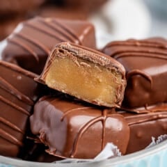 stacked butterscotch squares covered in chocolate in a light blue bowl.