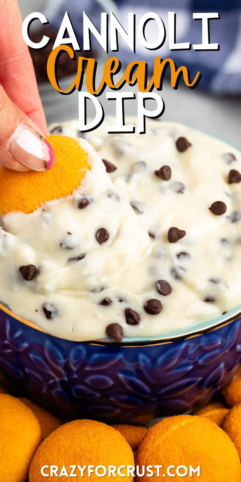 cannoli dip in a blue bowl with orange cookie wafers next to the bowl with words on the image.