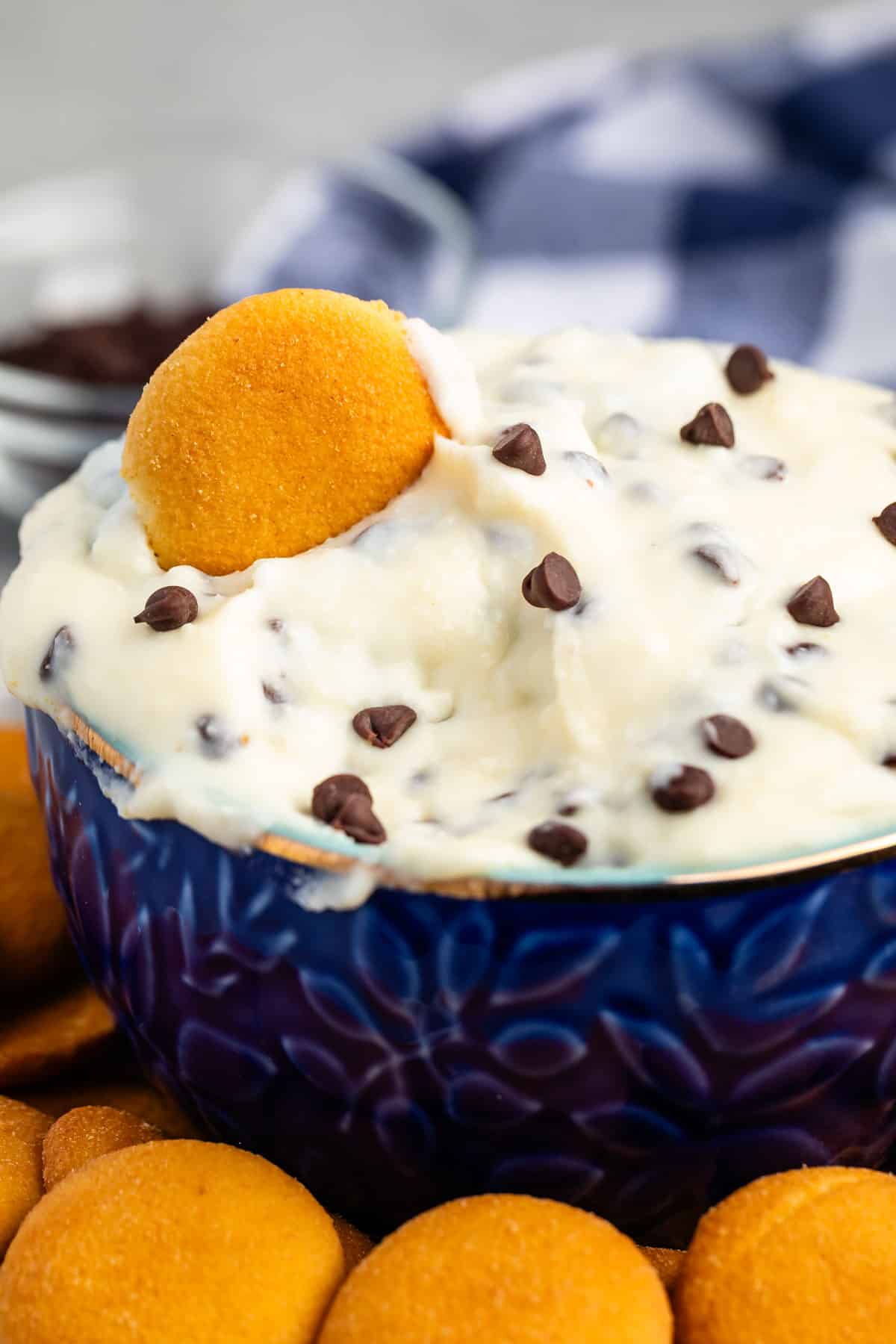cannoli dip in a blue bowl with orange cookie wafers next to the bowl.