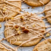 cookies laid out on parchment paper with icing and chopped pecans sprinkled over top.