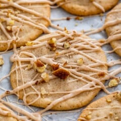 cookies laid out on parchment paper with icing and chopped pecans sprinkled over top.