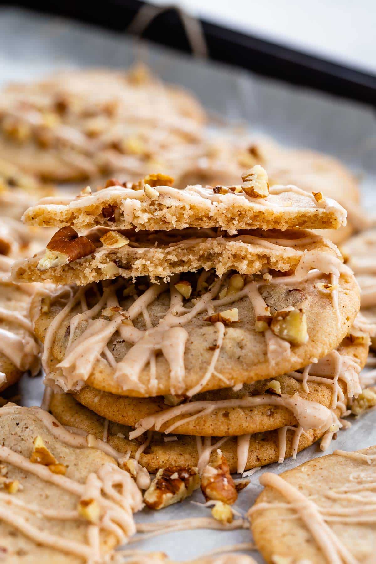 cookies laid out on parchment paper with icing and chopped pecans sprinkled over top.