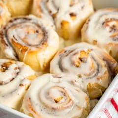 cinnamon rolls laid together in a white dish with icing on top.