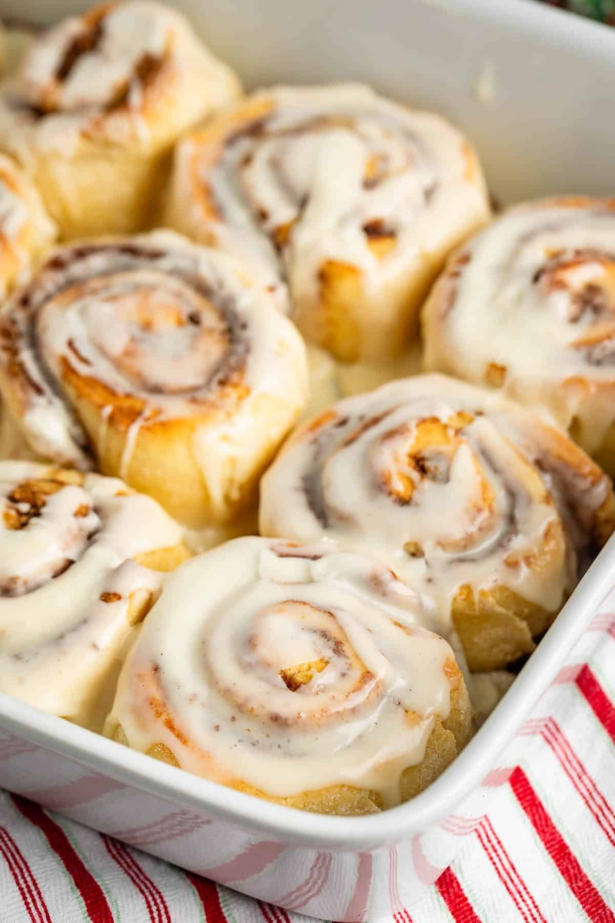 cinnamon rolls laid together in a white dish with icing on top.