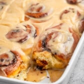 cinnamon rolls in a white pan with icing on top.