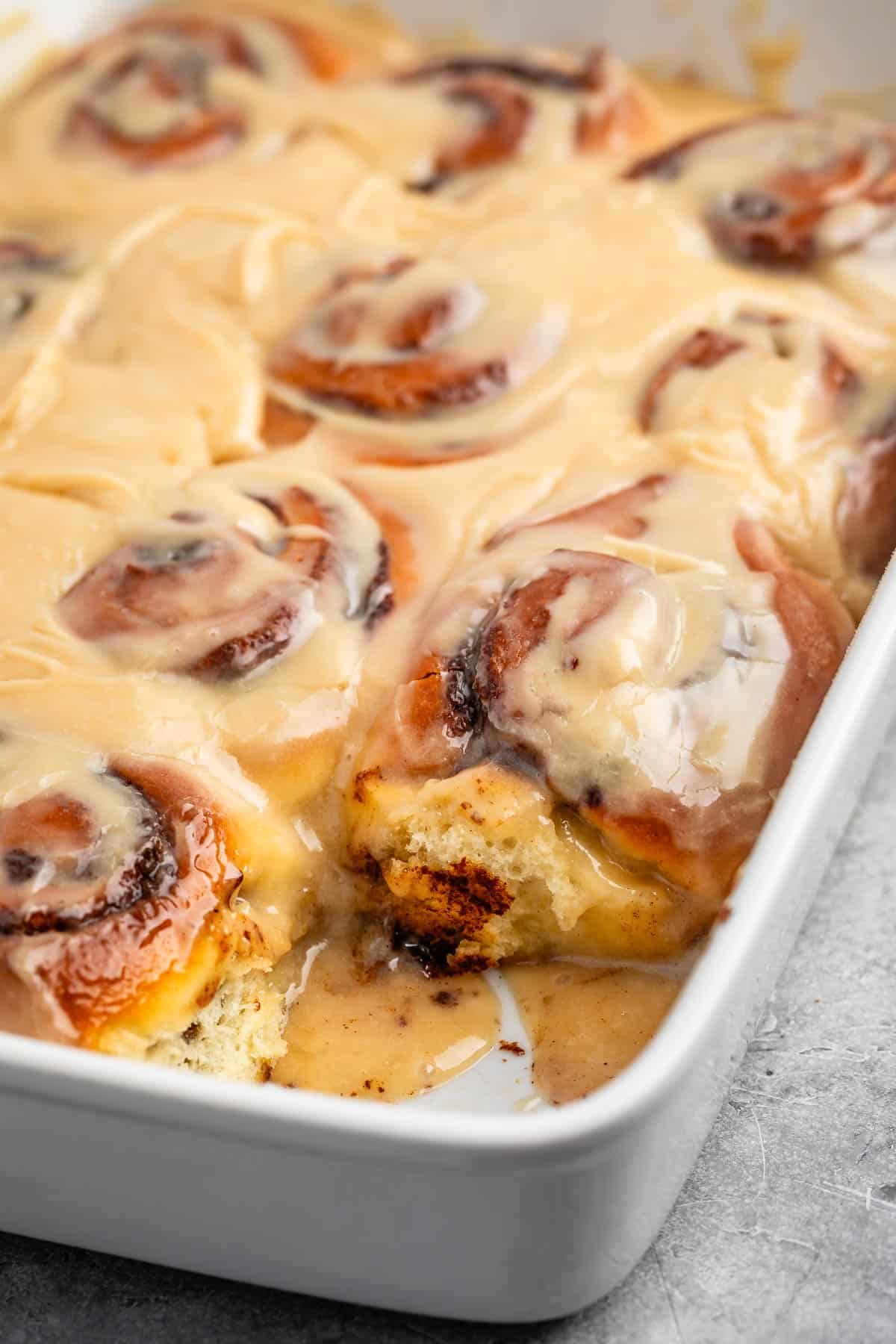 cinnamon rolls in a white pan with icing on top.