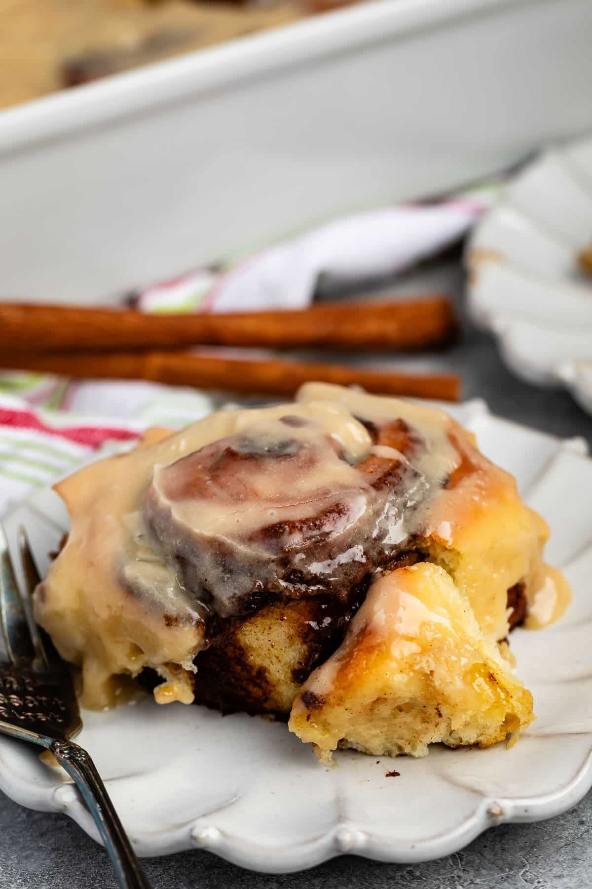 cinnamon roll on a grey plate with icing in top.