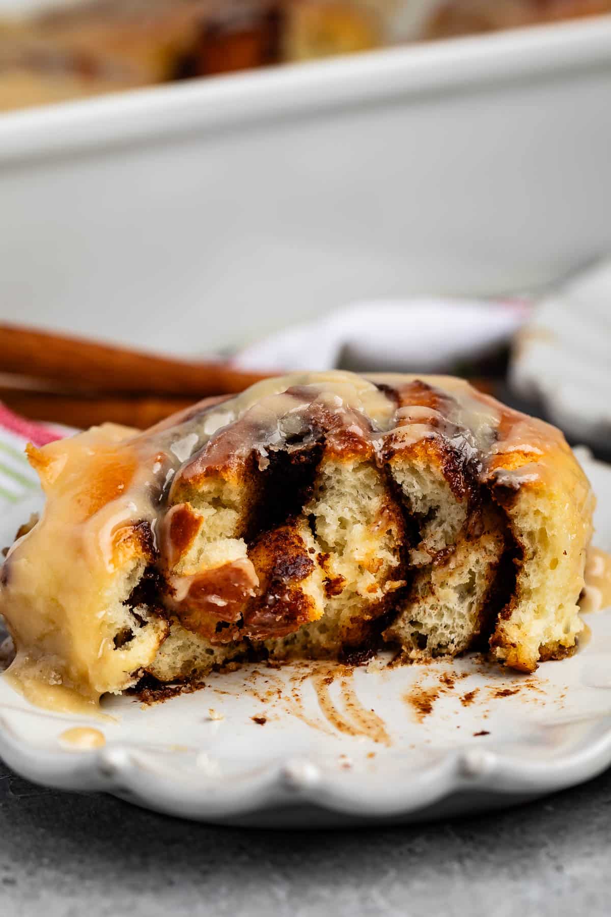 cinnamon roll on a grey plate with icing in top.
