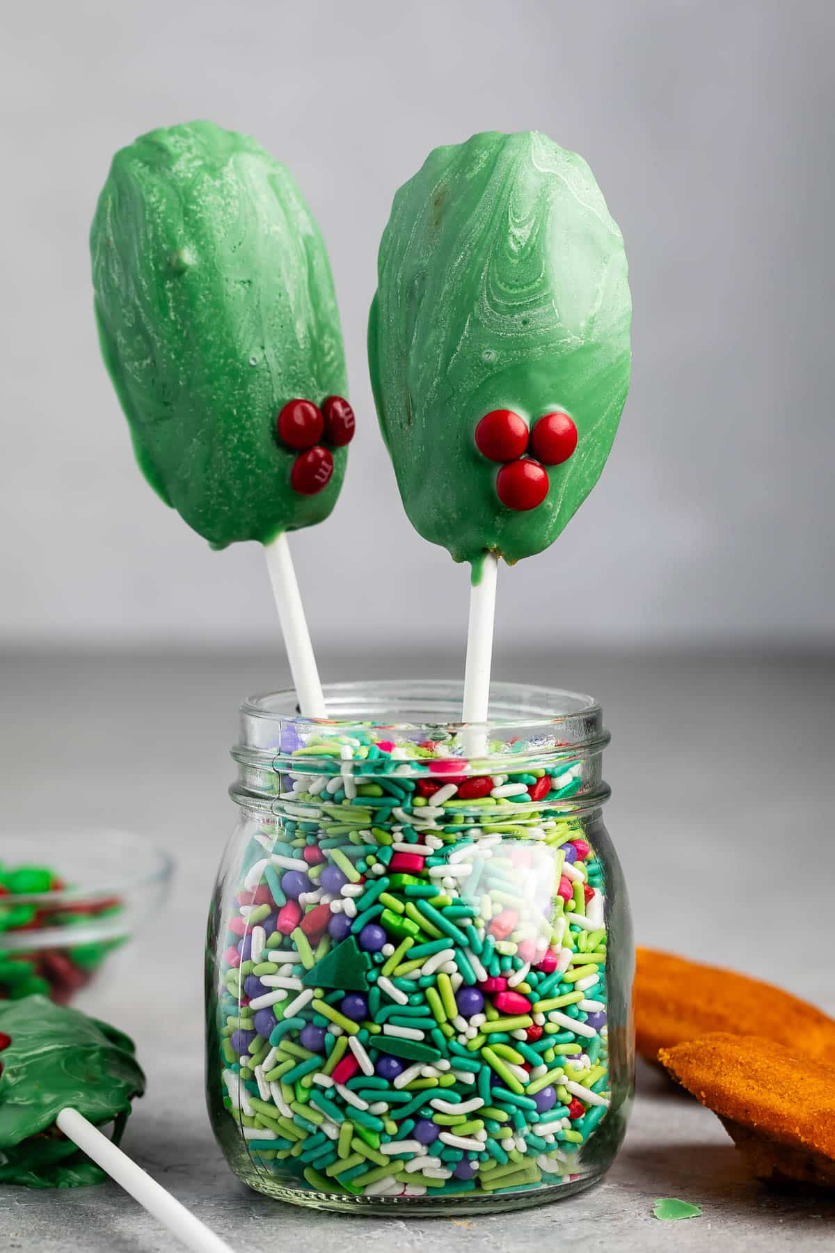 madeleines covered in green chocolate standing up in sprinkles.