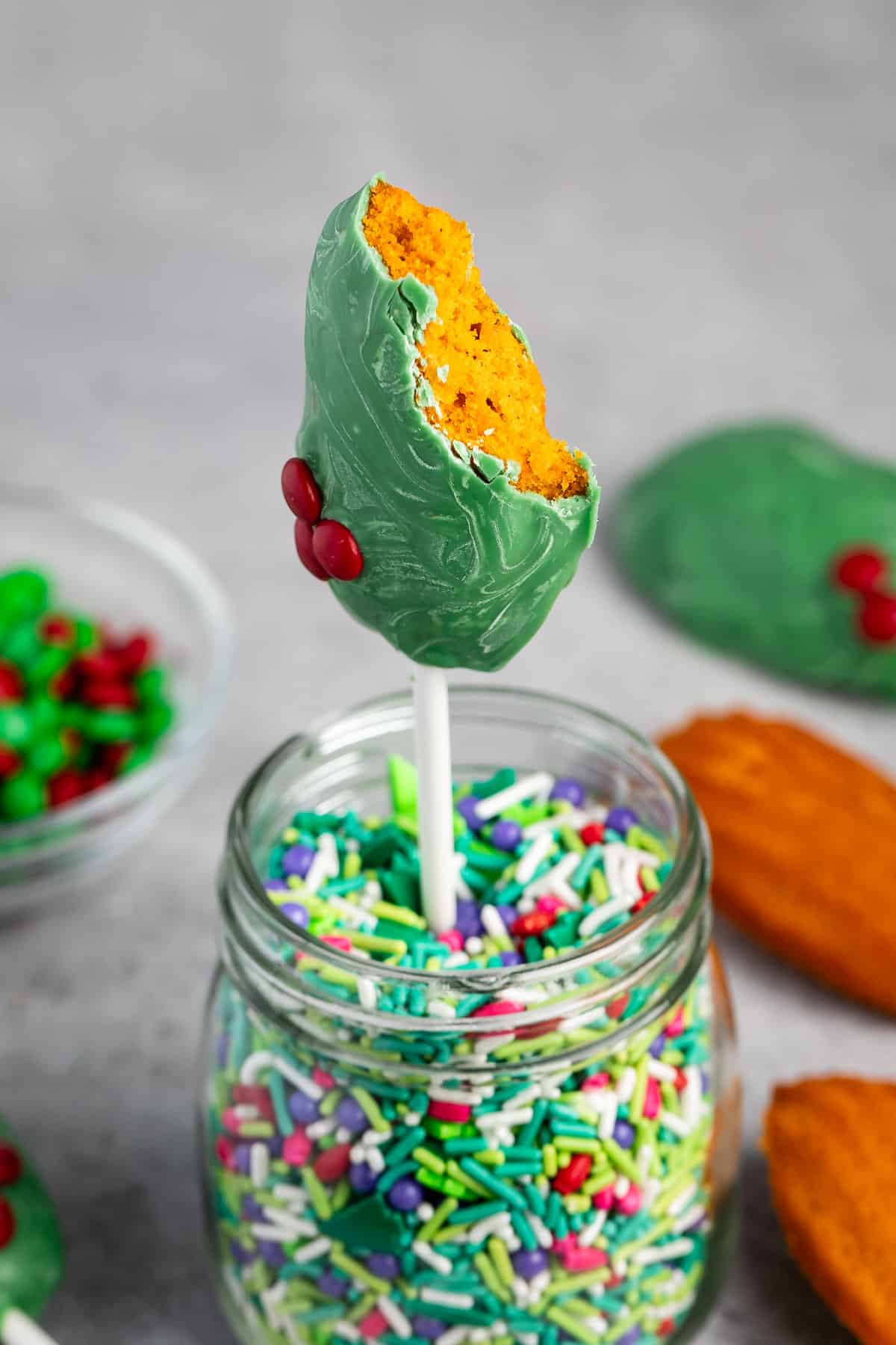 madeleines covered in green chocolate standing up in sprinkles.