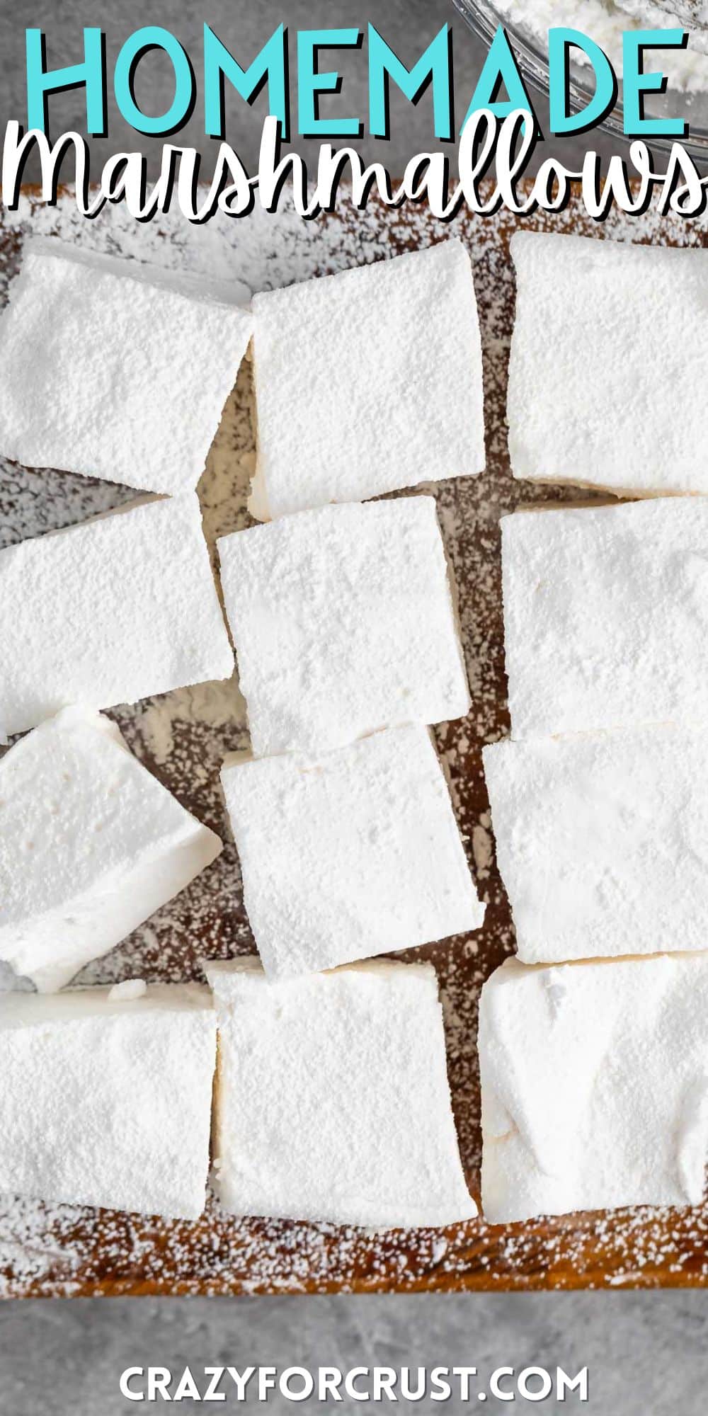 large homemade marshmallows laid on top of powdered sugar on a cutting board with words on the image.