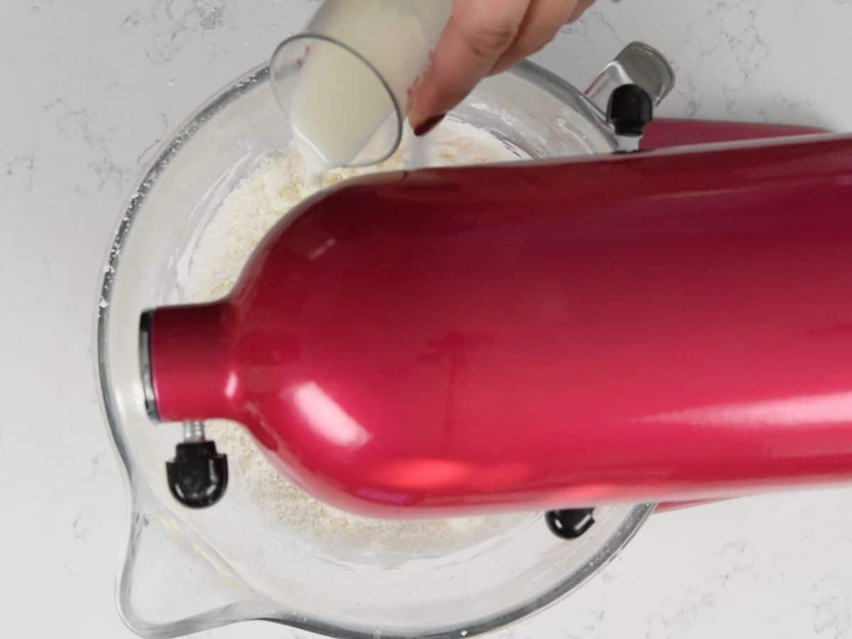 pouring milk into running pink mixer