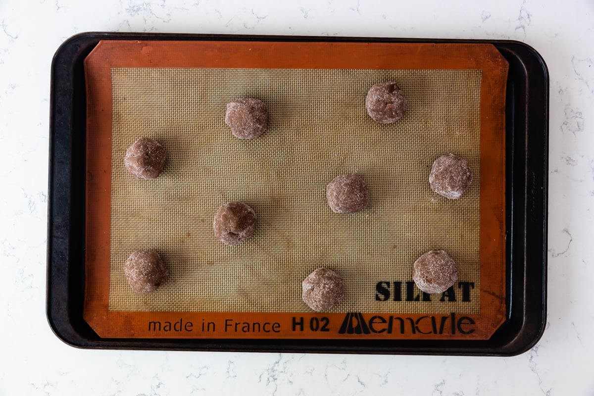 cookie dough balls on cookie sheet with silicone mat.
