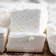 stacked marshmallows on a brown cutting board.