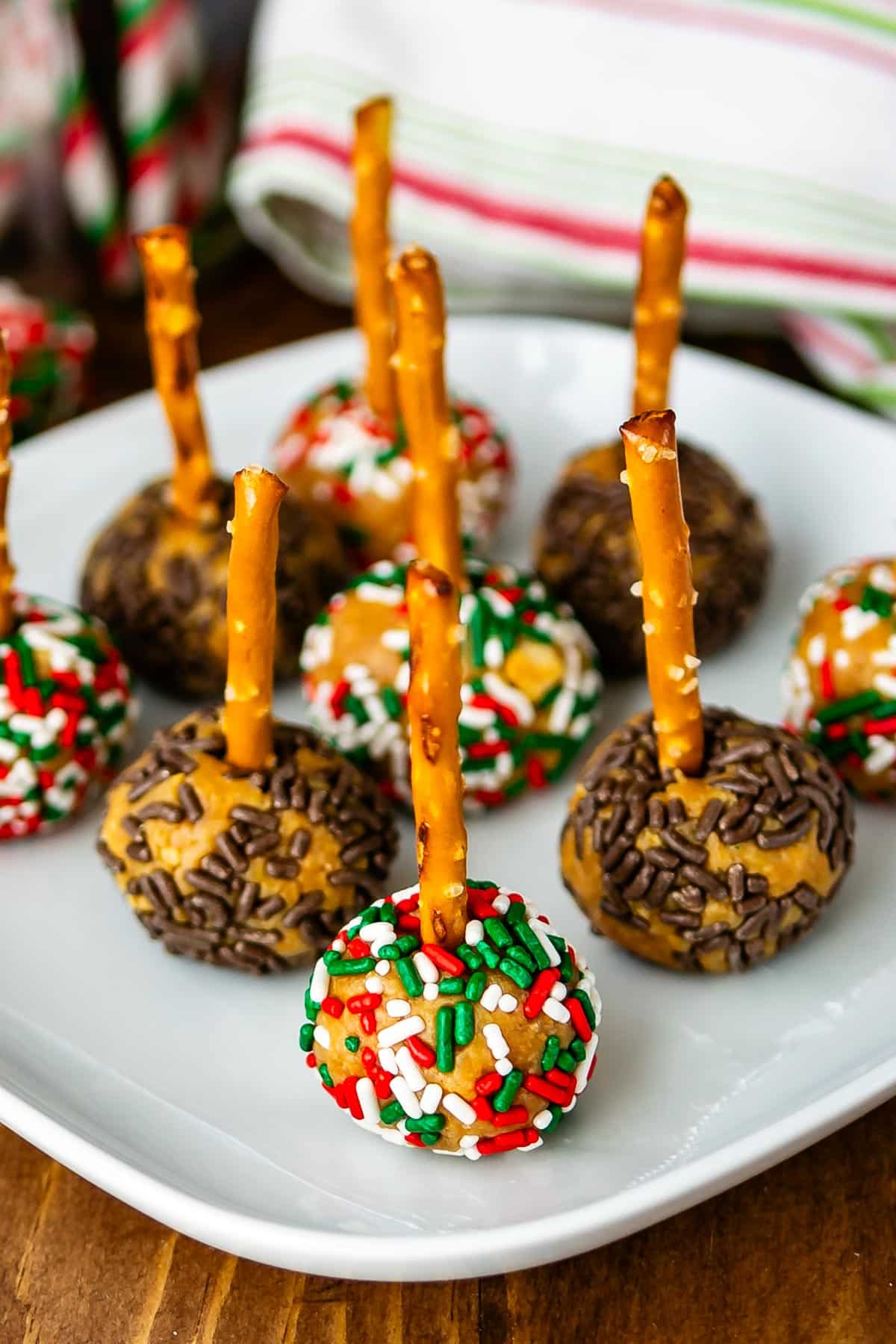 peanut butter balls with sprinkles pressed in the side on a pretzel stick.