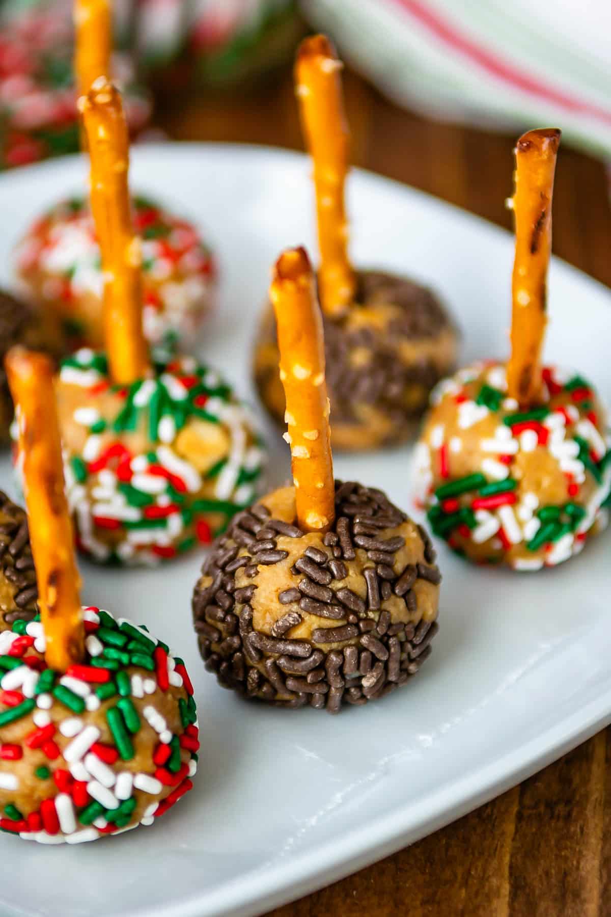 peanut butter balls with sprinkles pressed in the side on a pretzel stick.