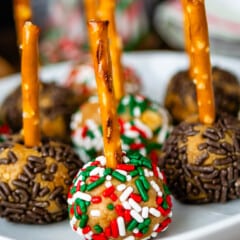 peanut butter balls with sprinkles pressed in the side on a pretzel stick.