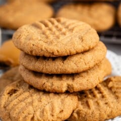 stacked peanut butter snickerdoodles on a white plate next to a spoonful of peanut butter.